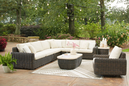 Outdoor wicker sectional with cushions and coffee table on a patio